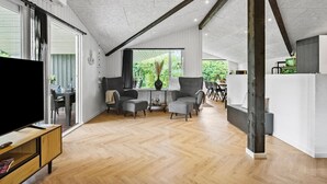Un salón espacioso con piso de madera, un televisor y un comedor con sillas y mesa.