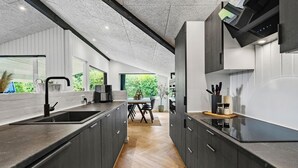 Una cocina moderna con armarios oscuros, una isla grande y vistas a zonas verdes.