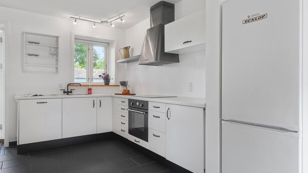 Una cocina moderna con armarios blancos, un refrigerador Bosch y un ventanal que proporciona luz natural.