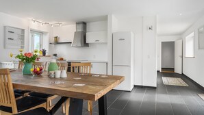 Una cocina moderna con armarios blancos, una campana extractora de acero inoxidable y un refrigerador DUNLOP.