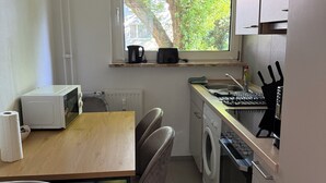 Una cocina compacta con ventana, microondas, fregadero, cocina y lavadora.