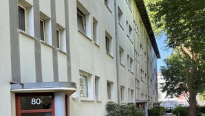 Un edificio con el número 80 en la puerta, un sendero pavimentado y vegetación.