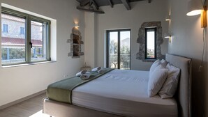 Ein Schlafzimmer mit einem Bett, zwei Fenstern, einer Steinsäule und einem Balkon.