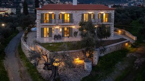 Ein Haus aus Stein mit zahlreichen Fenstern und Balkonen, umgeben von einer Steinmauer und einem Weg.