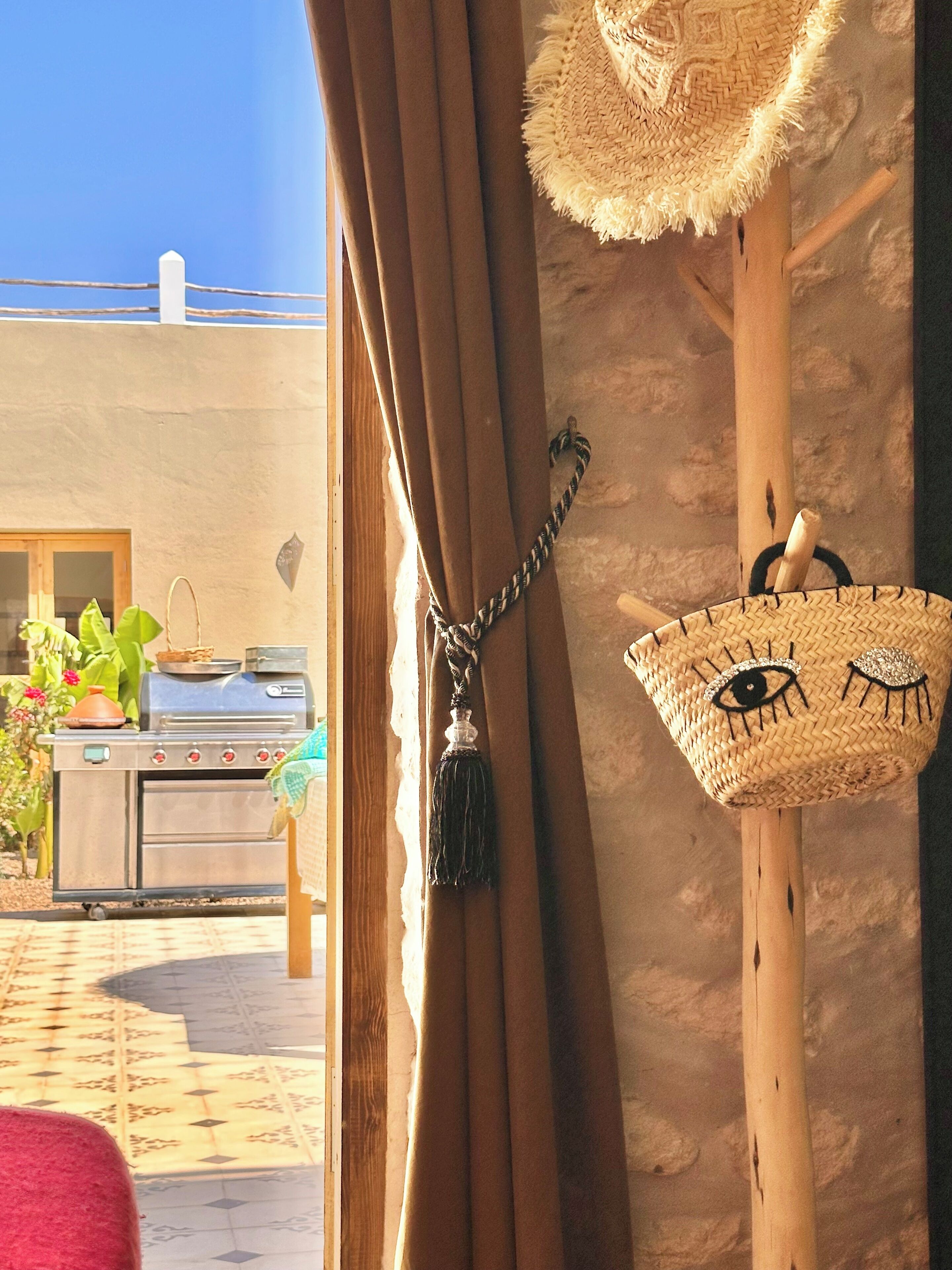 Ein Zimmer mit Blick auf eine Terrasse, einen Grill und einen wandmontierten Korb mit Gesichtsmotiv.