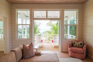 A room with a wooden deck, a sofa, a chair, and a view of the ocean.