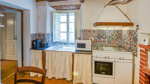 A kitchen with a white stove, a microwave, and a sink. There is a window with curtains, a door, and a chair. - Stunning home in Stazzema with WiFi (Stazzema)