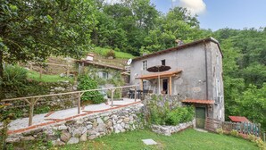 A rustic stone house with a patio, surrounded by lush greenery and hills. - Stunning home in Stazzema with WiFi (Stazzema)