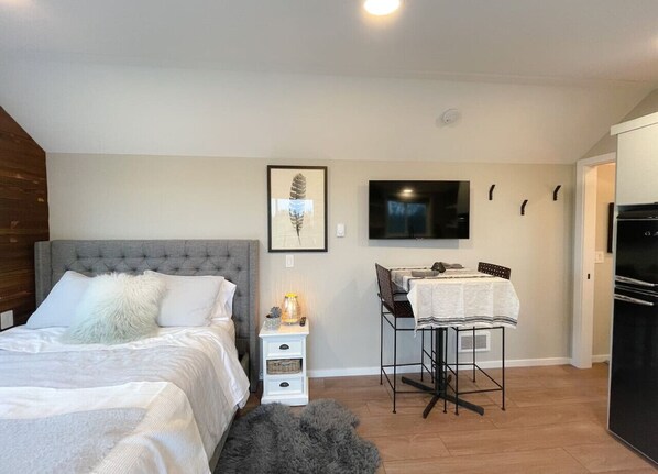 Een slaapkamer met een bed, nachtkastje en een klein bureau met stoel.
