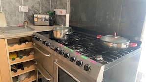 A kitchen with a gas stove, a toaster, and a pot on the stove.
