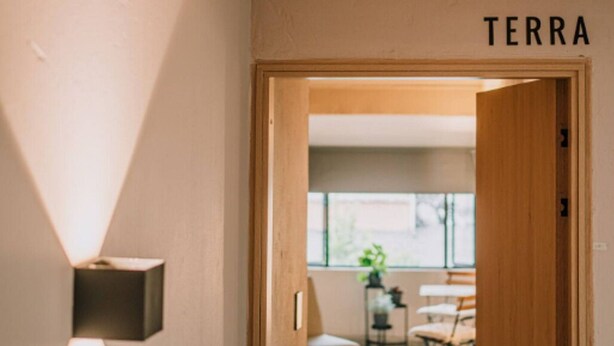 Un pasillo que conduce a una habitación con una puerta de madera que dice "TERRA".