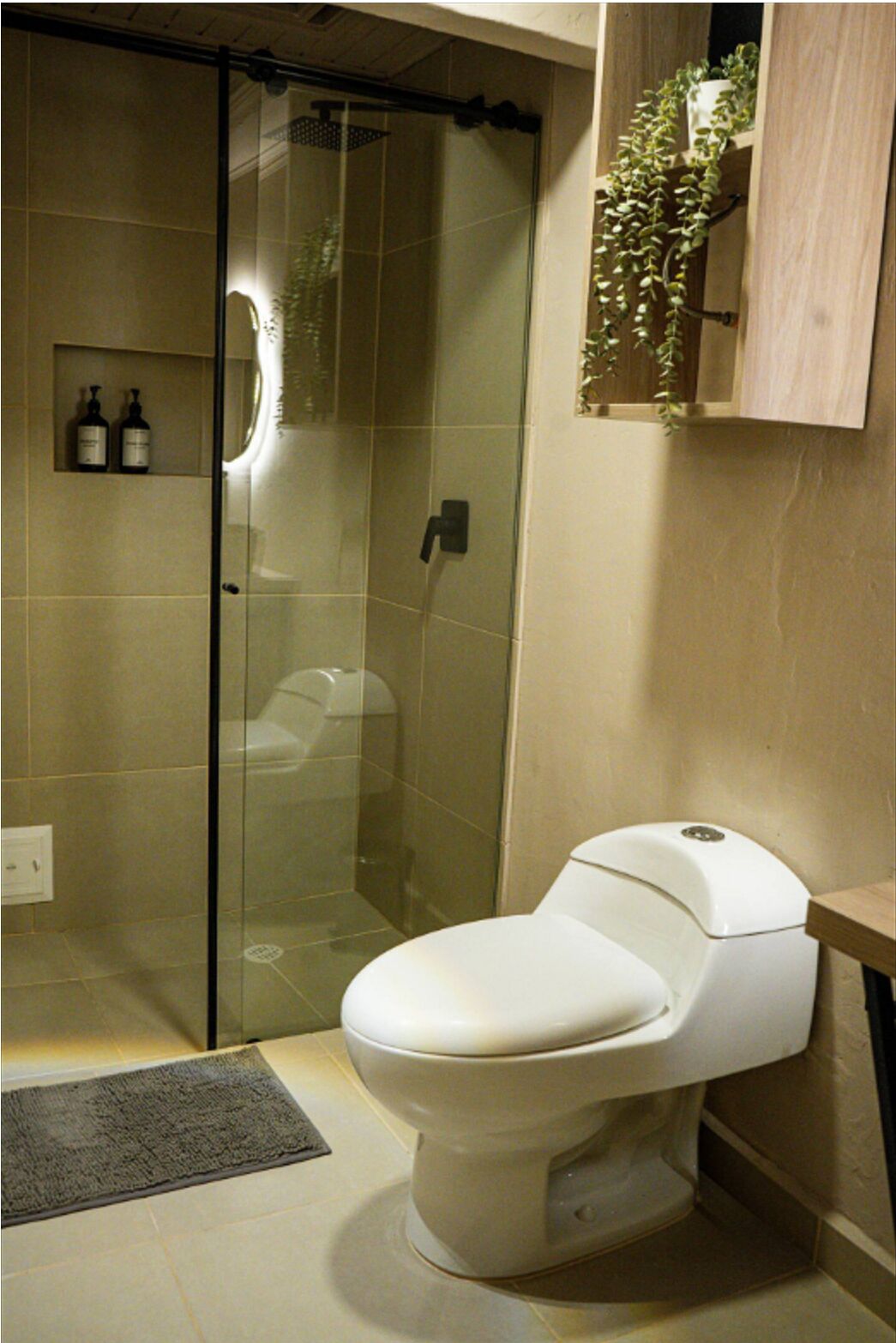 Une salle de bain moderne avec une douche à parois de verre, des toilettes et une petite étagère contenant des articles de toilette.