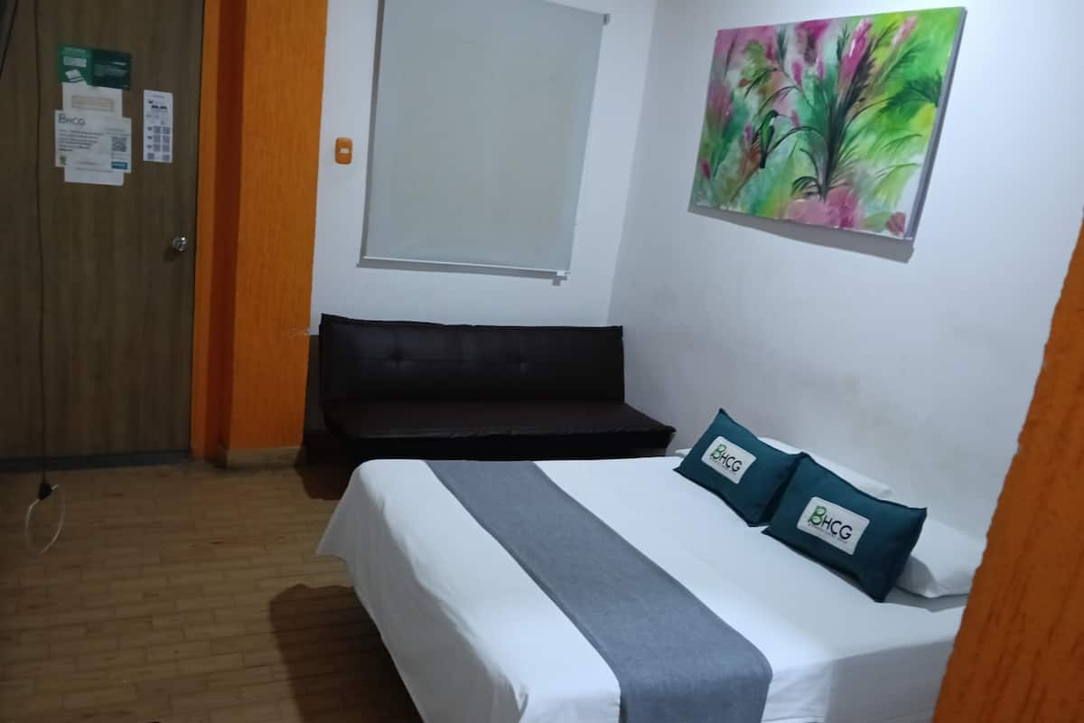 Una habitación de hotel con una cama, una ventana, un cuadro y una puerta.