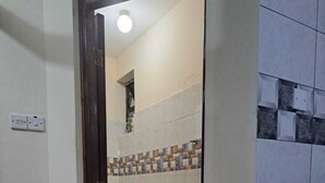 Un baño con inodoro, una alfombra roja y un cubo azul.