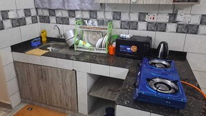 Una cocina con un lavamanos, un microondas, una estufa a gas y un escurreplatos.