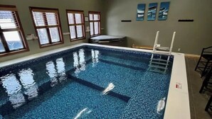 Una piscina interior con agua cristalina, un trampolín y suelo de baldosas.