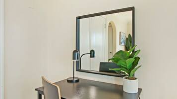 A desk with a mirror, a chair, and a potted plant.