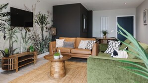A modern living room with a brown leather sofa, green armchair, and a wooden coffee table.
