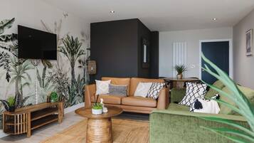 A modern living room with a brown leather sofa, green armchair, and a wooden coffee table.