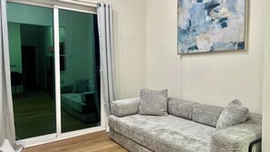 A living room with a grey sofa, a sliding glass door, and a painting on the wall.