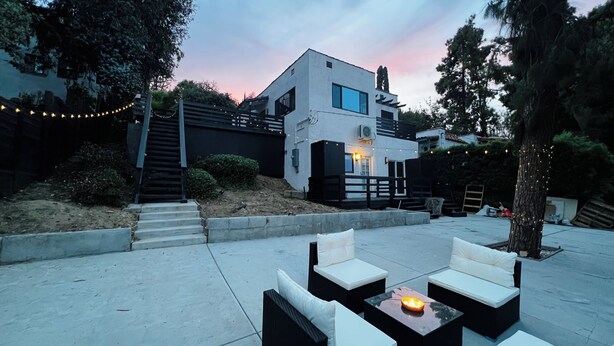 A modern house with a patio area featuring outdoor seating and a table with a candle.