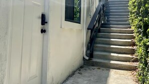 A white building with a door, windows, and a staircase leading up.