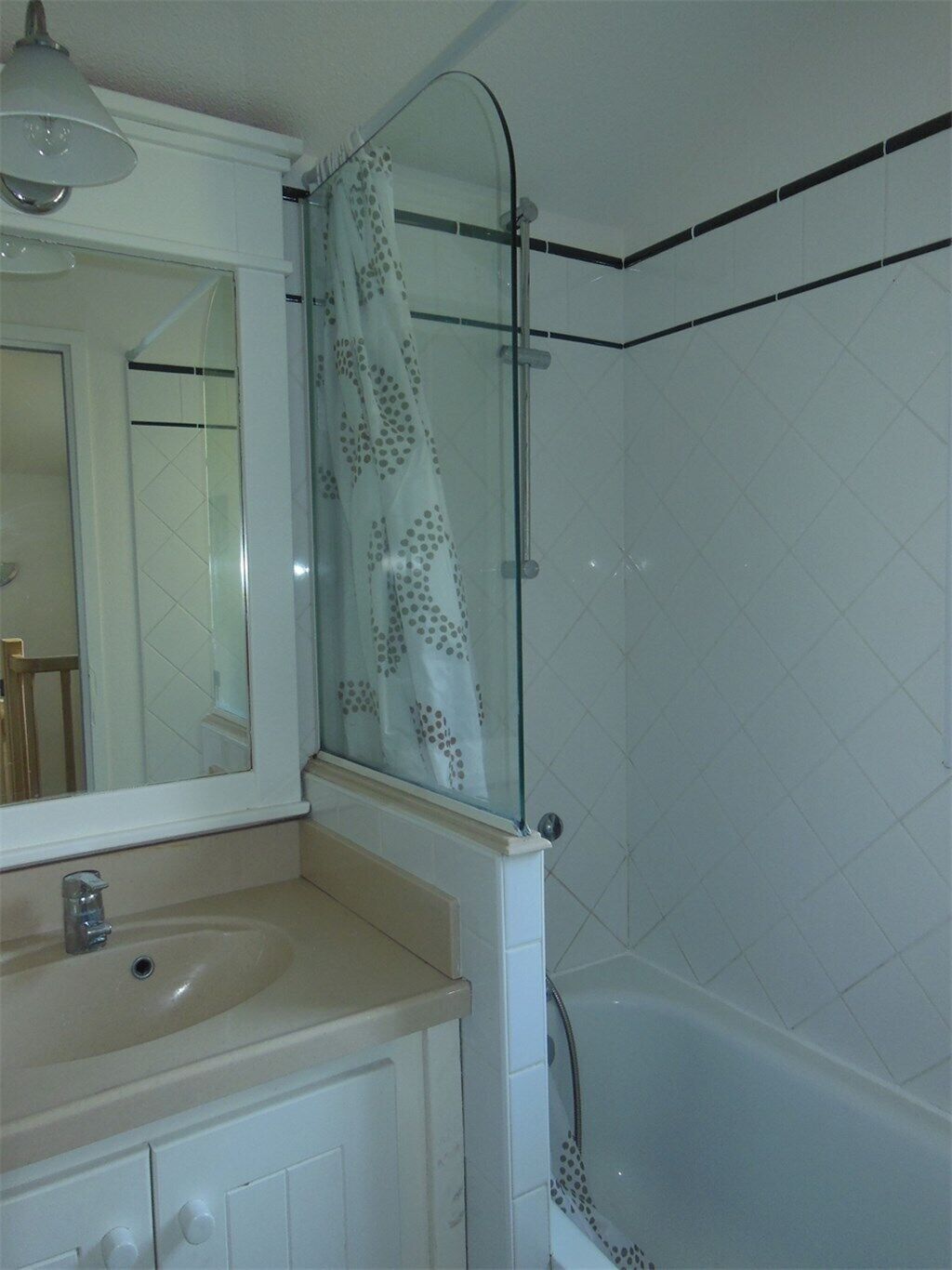 Une salle de bain avec une douche à parois de verre, un lavabo et un miroir.
