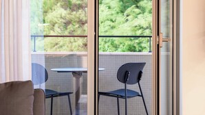 A modern room with a sliding glass door leading to an outdoor balcony. Inside, there is a sofa and a small table with a book.