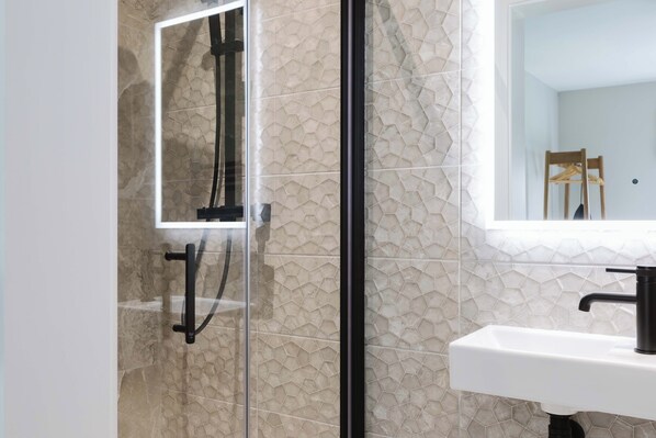 Une salle de bain avec une douche à parois de verre, un lavabo blanc et un miroir.