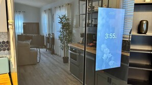Une cuisine moderne avec une horloge numérique affichant 15 h 55, une plante en pot et une table à manger en bois.