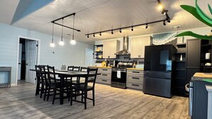 Une cuisine moderne dotée d’un îlot central, de planchers en bois et de luminaires suspendus.