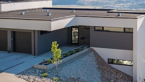 Un bâtiment moderne doté d’un toit plat, de grandes fenêtres et offrant une vue sur les montagnes en arrière-plan.