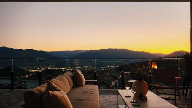 Un balcon avec un canapé et une table, offrant une vue sur le paysage urbain au coucher du soleil.