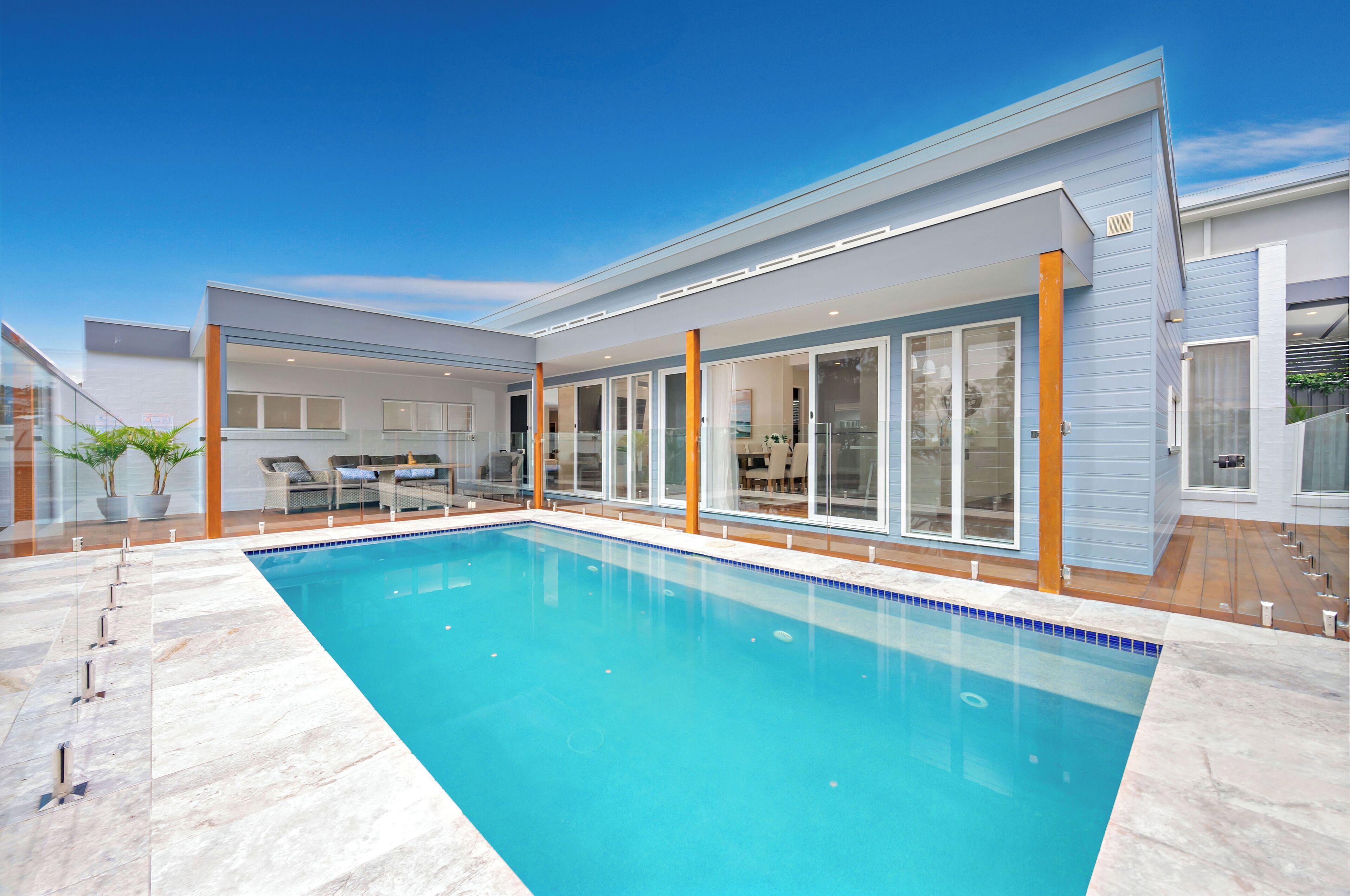 A modern house with a swimming pool, large glass doors, and a well-maintained garden.