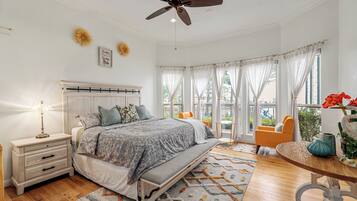 A bedroom with a bed, nightstand, and a view of the outdoors.