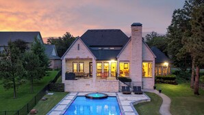 Ein Haus mit Swimmingpool, Steinaußenwand und gepflegtem Rasen.