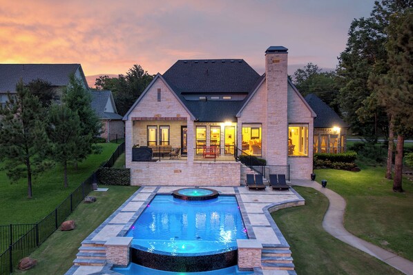 Una casa con piscina, fachada de piedra y césped cuidado.
