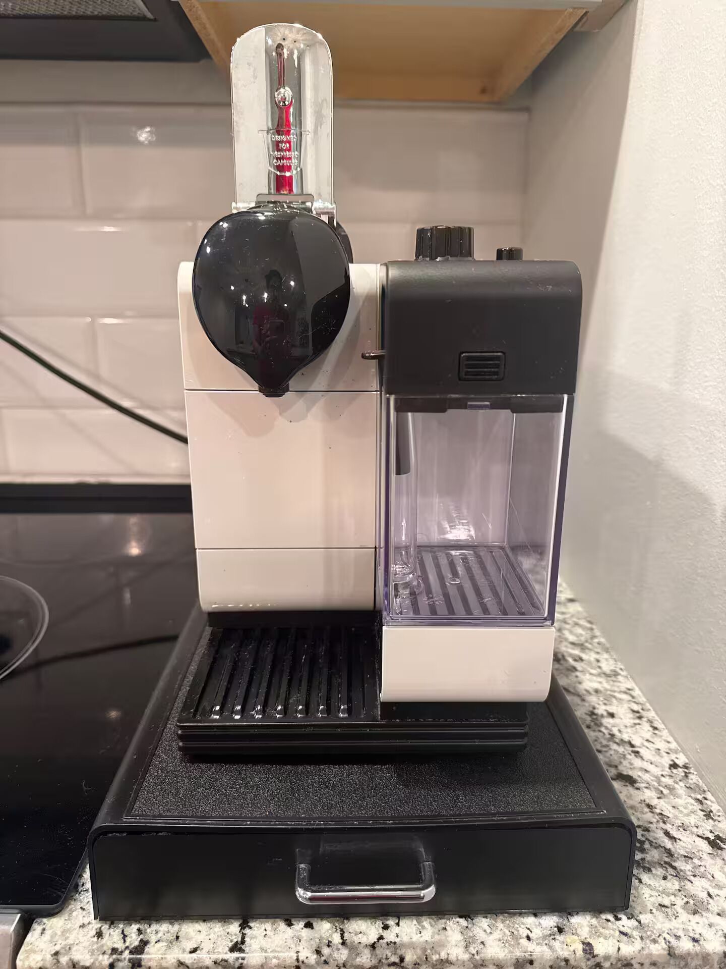 Una cafetera con depósito de agua transparente, bandeja de goteo negra y un asa en la base.