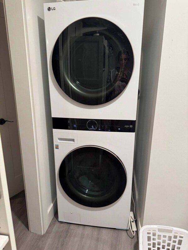 A stacked washer and dryer unit in a hallway.