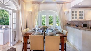Un comedor con una mesa de madera dispuesta para seis personas, rodeado de sillas color crema.