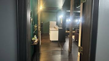 A hallway with a wooden floor leading to a living area with a sofa and a coffee table.