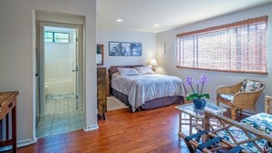 Un dormitorio con cama, una silla, una mesa y ventana con persianas.