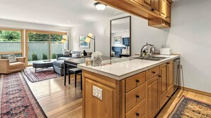 Une cuisine moderne avec des meubles en bois, un grand îlot central et un coin repas comprenant un canapé et des chaises.