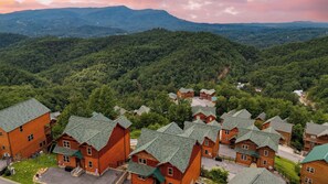 A lodge with multiple wooden cabins, surrounded by forested hills. - All Fun & Games by Avantstay Indoor Pool, Game Room, Theater, Mountain Views Near Pigeon Forge & Dollywood (Sevierville)