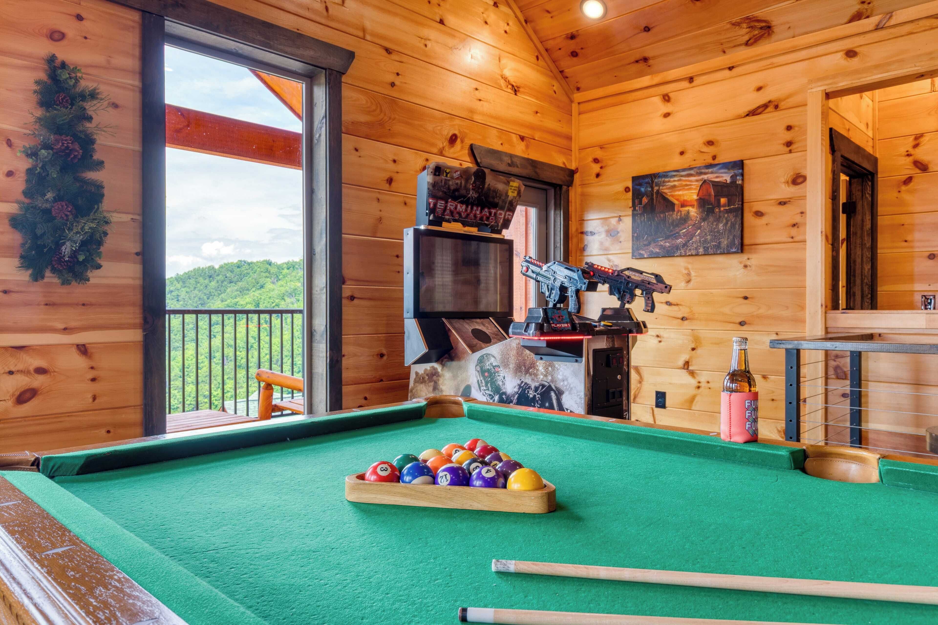 A pool table with balls, a pool cue, and a bottle of FUEL.