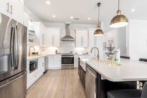 A modern kitchen with stainless steel appliances, white cabinetry, and a marble island. - 2 Homes in Destin by Avantstay   Sleeps 30, Private Pool+hot Tub, Game Room, Outdoor Bar, Walk to Beach (Destin)