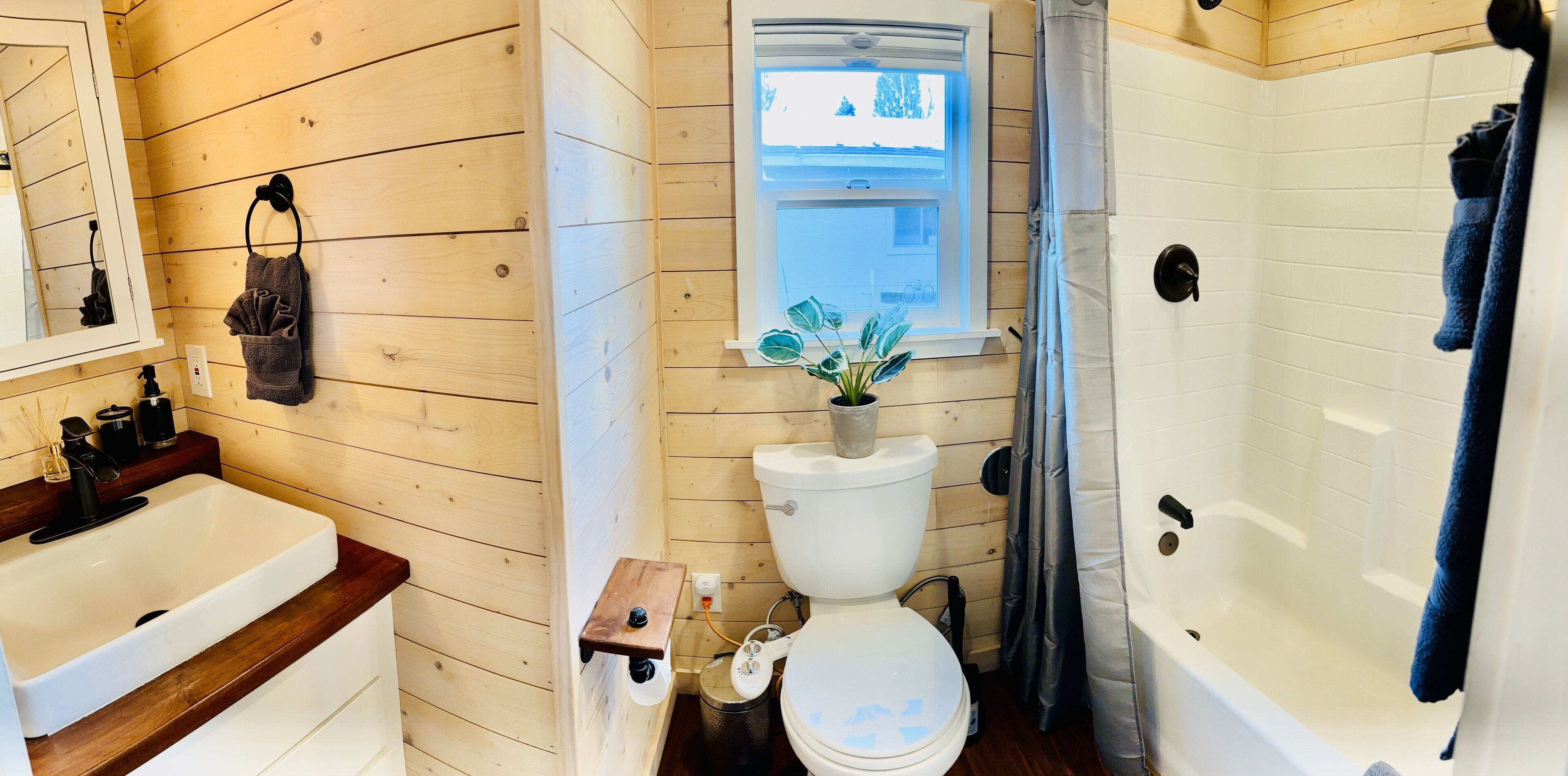 A wooden-paneled bathroom with a white sink, toilet, and bathtub.