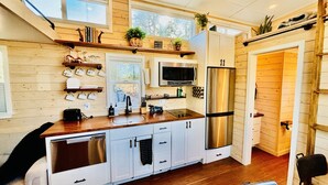 A modern kitchen with white cabinets, a stainless steel refrigerator, and a microwave. - Couple’s retreat in Tiny Home w soaking tub/beach at Upper Lake (Upper Lake)