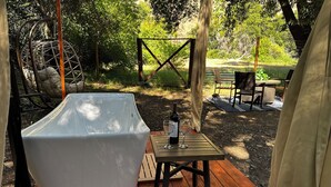 A wooden deck with a white bathtub, a table with two wine glasses and a bottle, and outdoor furniture. - Couple’s retreat in Tiny Home w soaking tub/beach at Upper Lake (Upper Lake)