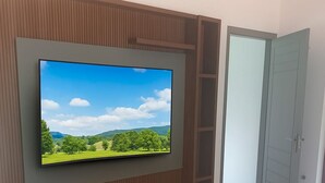 Ett modernt vardagsrum med en platt-TV som är monterad på en väggpanel av trä, ett grått skåp under och ett klinkergolv.